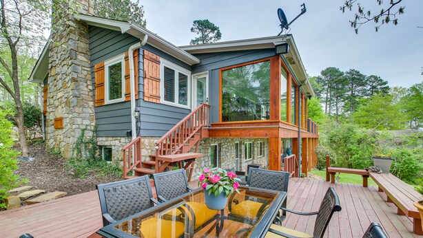 A deck with a glass-top table and chairs, surrounded by stone walls and wooden railings.