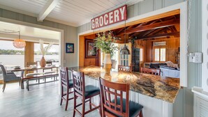 A kitchen with a granite countertop, wooden chairs, and a 'GROCERY' sign.