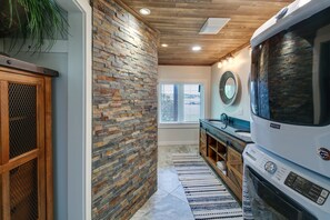 Kitchen area with a stone wall and wooden ceiling, featuring a refrigerator, oven, sink, and ample workspace.