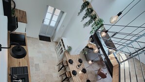 A modern kitchen with a dining area, wooden flooring, and a staircase.