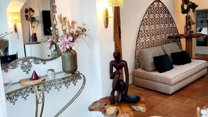 Una sala de estar acogedora con un sofá, un espejo decorativo, una lámpara y un diseño de pared original.