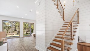 A modern interior with a wooden staircase, large windows, and a view of the outdoors. - Coastal Lake View & Access! BIGGEST in Rosemary Beach PRIVATE Pool ! Sleeps 18 (Rosemary Beach)