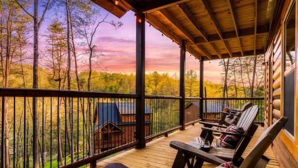 A wooden deck with outdoor seating and a view of a forest. - Luxury Indoor Pool Cabin Near Gatlinburg - Hot Tub, Game Room & Fire Pit (Sevierville)