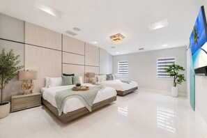 Een moderne slaapkamer met twee bedden, een flatscreen televisie en een groot raam met zonwering.