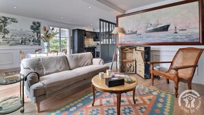 Ein Wohnzimmer mit einer Couch, einem Sessel, einem Couchtisch und einem Gemälde eines Schiffes an der Wand.