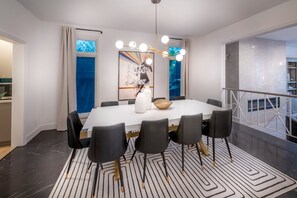 A modern dining area with a white table, black chairs, and a patterned rug. - Reef Mall (Marina del Rey)