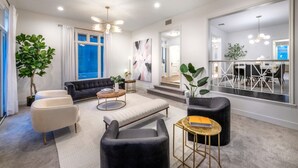 A modern living room with a sofa, armchairs, a coffee table, and a dining area with a table and chairs. - Reef Mall (Marina del Rey)
