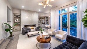 A modern living room with a fireplace, a coffee table, sofas, and a dining area visible through large windows. - Reef Mall (Marina del Rey)