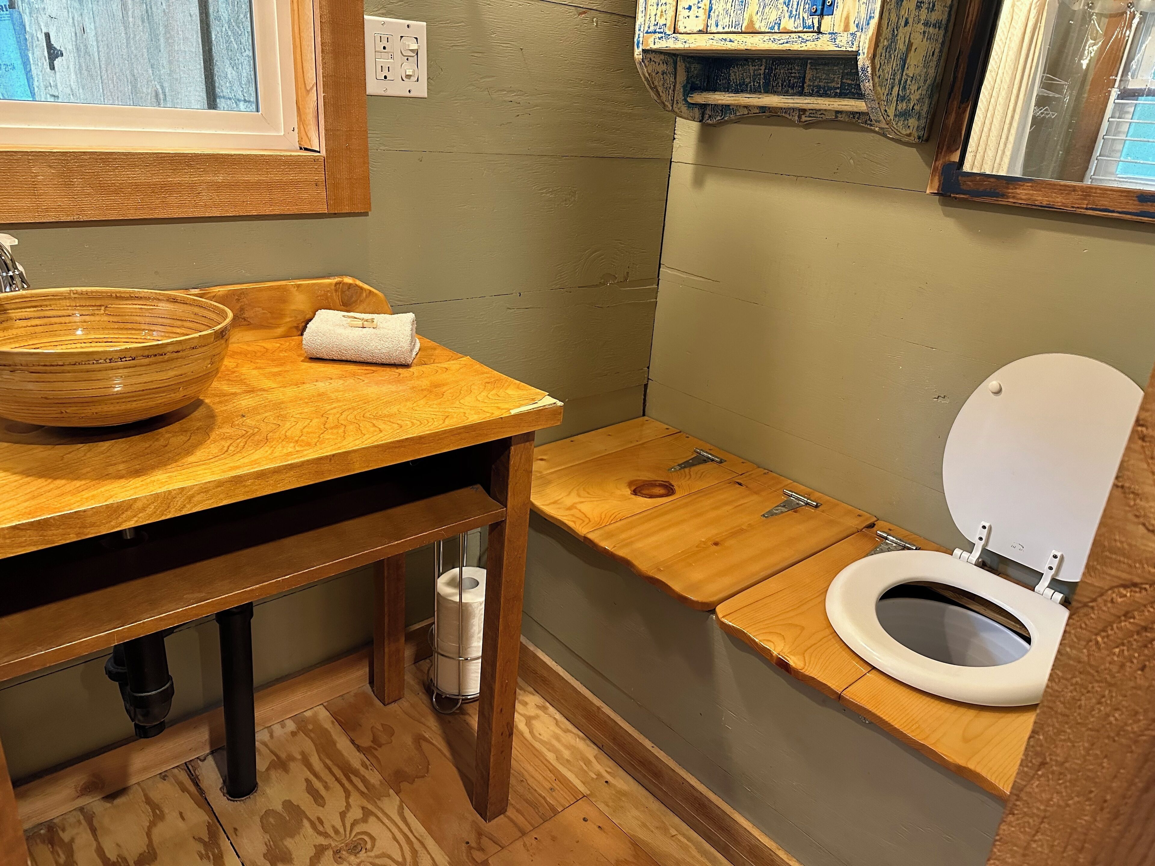 Une salle de bain avec un meuble-lavabo en bois, un lavabo sur colonne, des toilettes et un porte-serviettes.