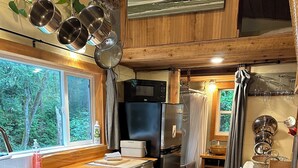 Een compacte keuken met een houten aanrechtblad, roestvrijstalen apparatuur en uitzicht op de omgeving.