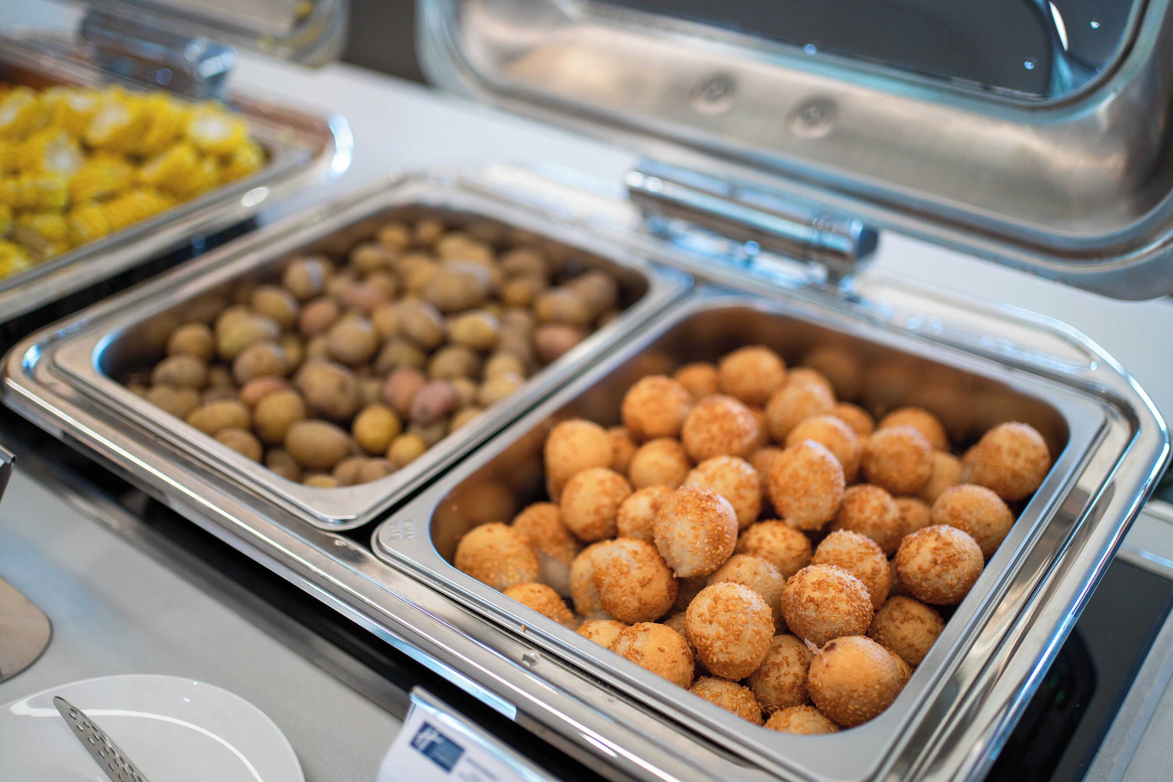 Un bufé con diversos alimentos en recipientes metálicos.