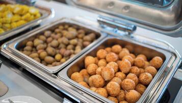 Un bufé con diversos alimentos en recipientes metálicos.
