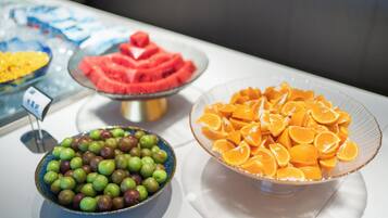 A buffet with various fruits including apples, oranges, and watermelon.