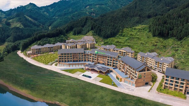 A Holiday Inn Express hotel with multiple buildings, a parking area, and a lake in the foreground.