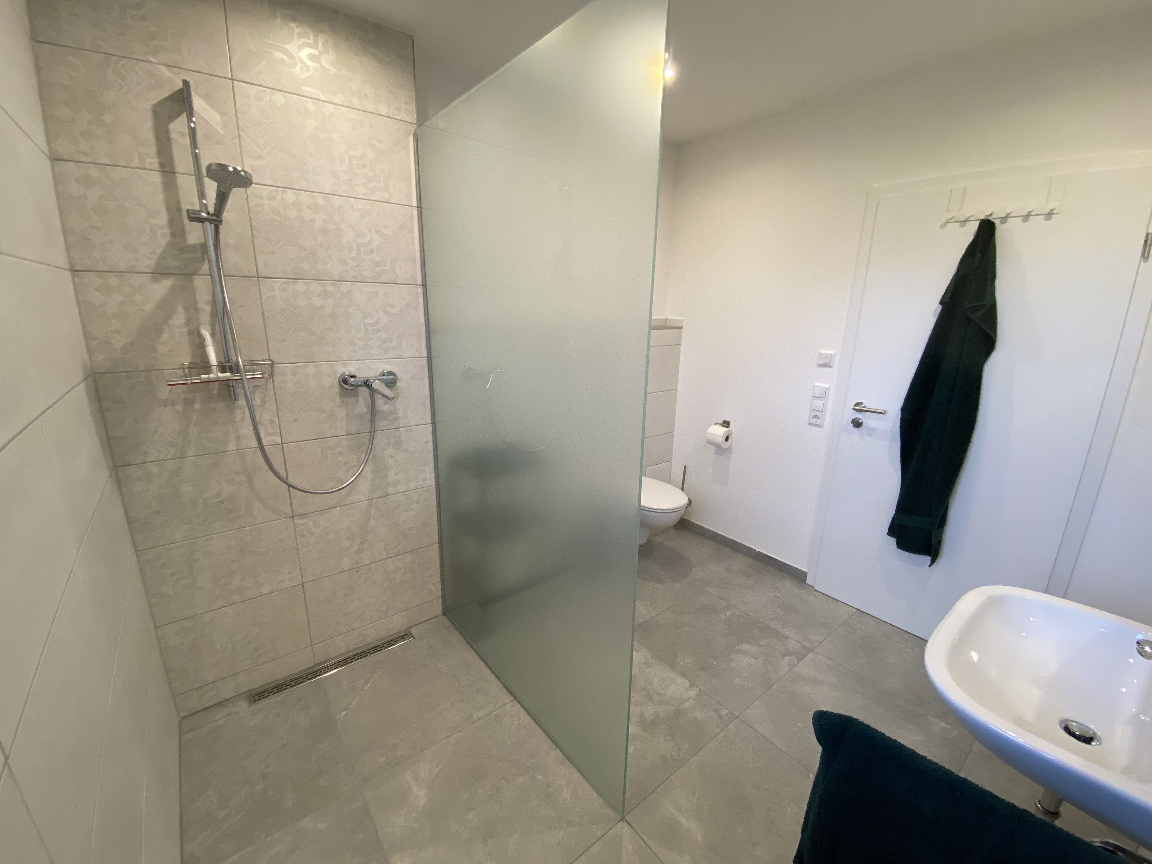 Et badeværelse med bruser, toilet og håndvask.