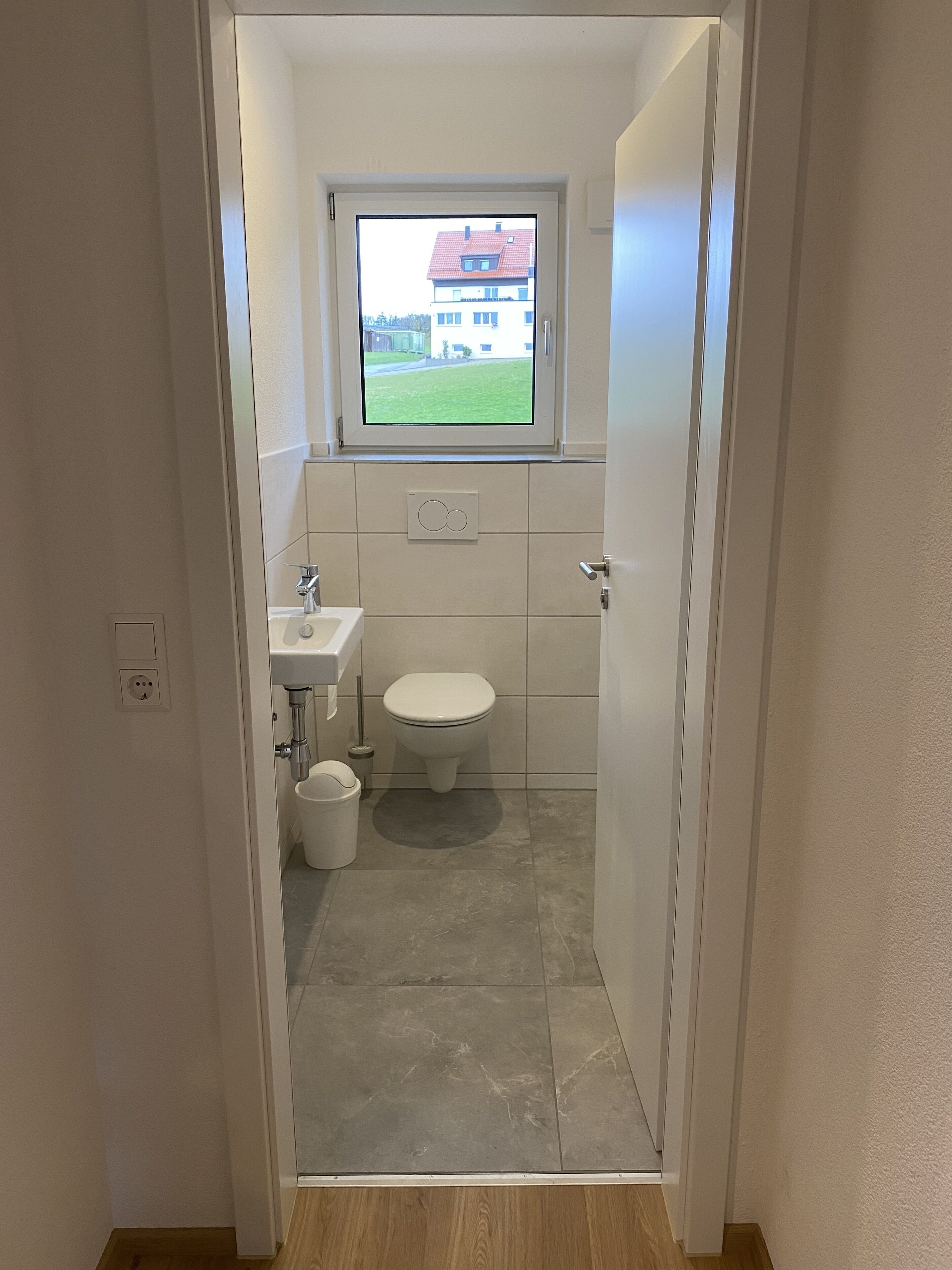 Un baño pequeño y moderno con inodoro, lavamanos y ventana.