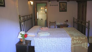 Un dormitorio con una cama, una mesita de noche, una lámpara, un florero con una rosa y un cuadro en la pared.