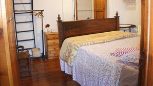 Un dormitorio con una cama de madera, un aparador, un espejo y una escalera.
