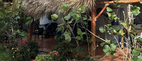 A house with a thatched roof, a balcony, and a garden with tropical plants.
