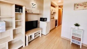 A compact living space with a kitchenette, a flat-screen TV, and a small dining area.