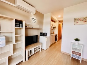 Cozy living space with a bench, flat-screen TV, and small refrigerator.