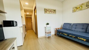 A compact living space with a kitchenette, a sofa, and a small table.