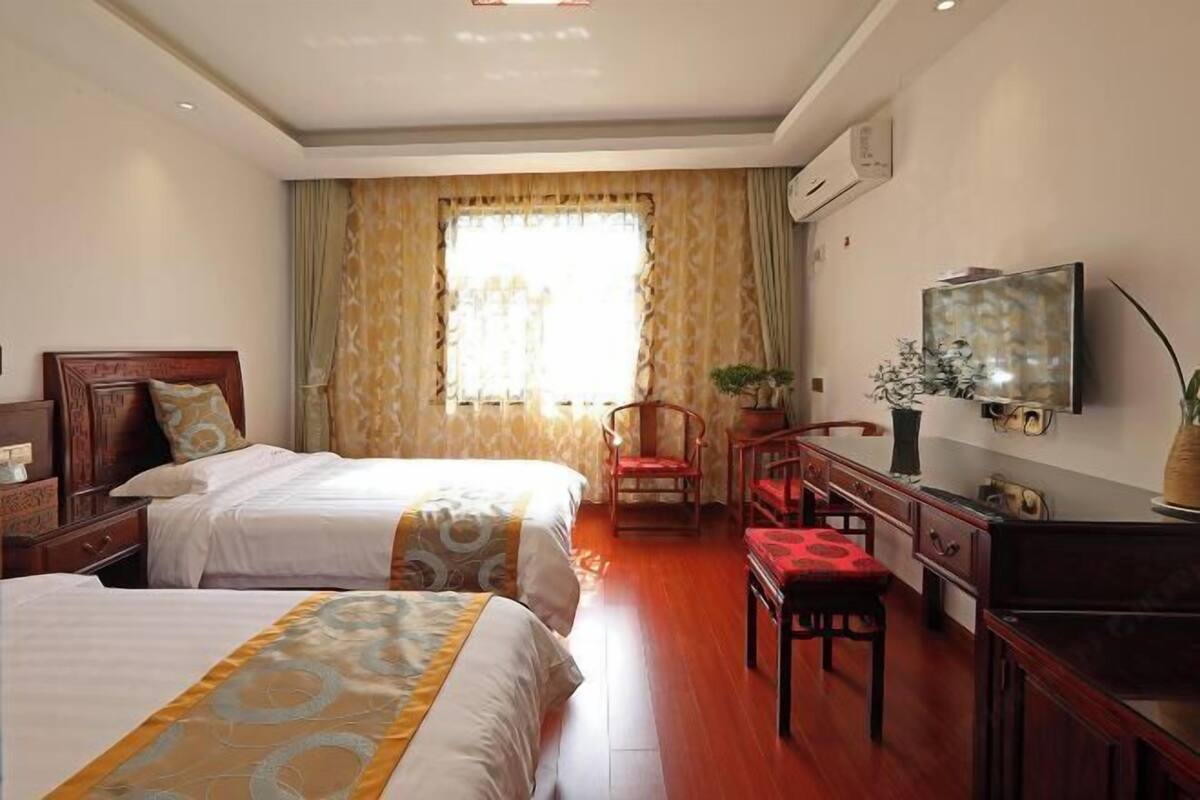 Une chambre d’hôtel avec deux lits, un bureau avec une chaise, une télévision et une fenêtre avec des rideaux.