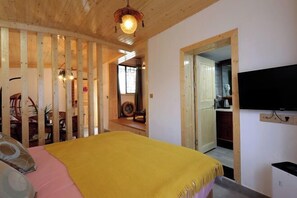 A bedroom with a bed, a wooden ceiling, a TV, and a kitchen area visible through an open door. - Jufulai Inn Jiuhua Mountain (Qingyang)