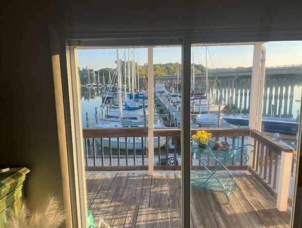 Enjoy breathtaking views of the marina from this room's expansive window, featuring a deck with a table and chairs.