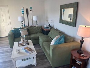 Relax in this inviting living room with a sofa, side tables, and a large mirror.