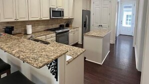 Una cucina moderna con mobili bianchi, piani in granito e elettrodomestici in acciaio inossidabile.