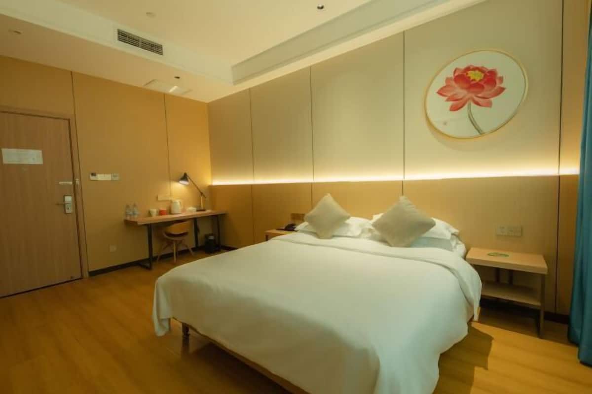 Ein Hotelzimmer mit Bett, Nachttisch und Schreibtisch mit Lampe.
