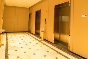 A hallway with two elevators, a tiled floor, and a trash bin. - Xinzhou Panhua Hotel Theme Department (Xinzhou)