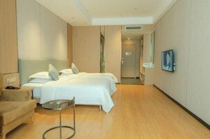 Habitación de hotel con cama, una silla, una mesita y un cuadro en la pared.