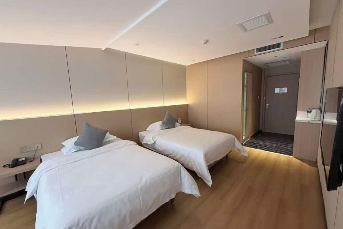 Ein Hotelzimmer mit zwei Betten, einem Nachttisch, einem Schreibtisch und einem Kleiderschrank.