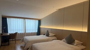 Habitación de hotel con dos camas, un escritorio y una silla.