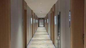 Un pasillo largo y estrecho con puertas de madera a ambos lados y un suelo con diseño de mármol.