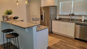 A modern kitchen with a central island, stainless steel appliances, and a window providing natural light. - Charming Lake Home (Lake City)