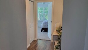 A narrow hallway leading to a bedroom with a bed and a window. - Charming Lake Home (Lake City)