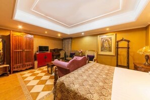 Quarto de hotel com uma cama grande, uma escrivaninha, uma cadeira, um guarda-roupa e uma televisão.