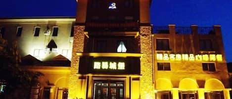 A hotel with a prominent entrance, a signboard, and a well-lit facade.