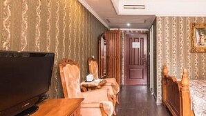 Une chambre d’hôtel équipée d’une télévision, d’un lit en bois, d’un bureau avec une chaise et d’une armoire.