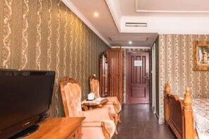 Una habitación de hotel con televisión, cama de madera, escritorio con silla y armario.