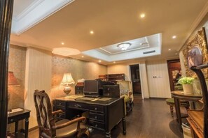 Quarto de hotel com escrivaninha, cadeira, luminária e iluminação no teto.