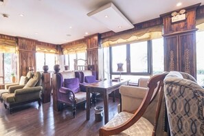Une pièce avec un plancher en bois, une table à manger avec des chaises et une fenêtre avec des rideaux.
