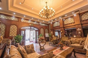 A grand lobby with ornate wood paneling, a chandelier, and plush seating. - Luyi Chengbao Hotel Tongling (Tongling)