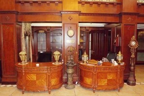 Una zona de recepción con dos mostradores de madera ornamentados, un espejo grande y un reloj en la pared.
