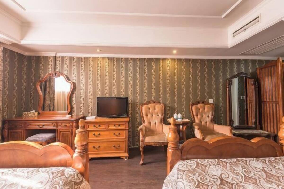 Habitación de hotel con dos camas, televisión, cómoda y dos sillas.