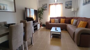 Ein Wohnzimmer mit einer Couch, einem Couchtisch, einem Fernseher und einem Essbereich mit Stühlen.