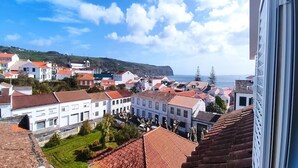 Eine Küstenstadt mit terrakottafarbenen Dächern, wolkenlosem Himmel und Blick auf das Meer.